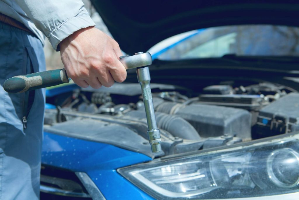 mechanic holding wrench over engine